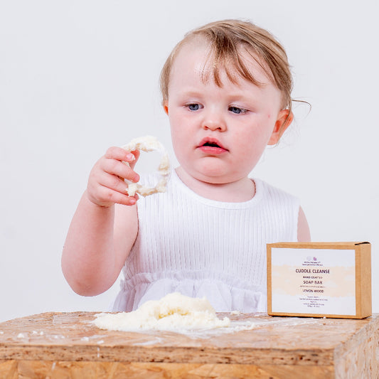 Toddler examining Official True Beauty Cuddle Cleanse Lemon Wood soap bar