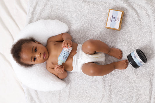 BABY LAY DOWN ON A PILLOW HOLDING A PRODUCT