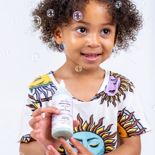 Child holding a bottle of miracle magic serum with bubbles around, wearing a colorful shirt.