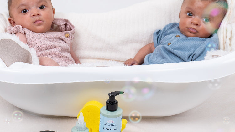 Twin babies sitting in a small bathtub with Official True Beautyproducts displayed in front, with rubber duck toys and bubbles.